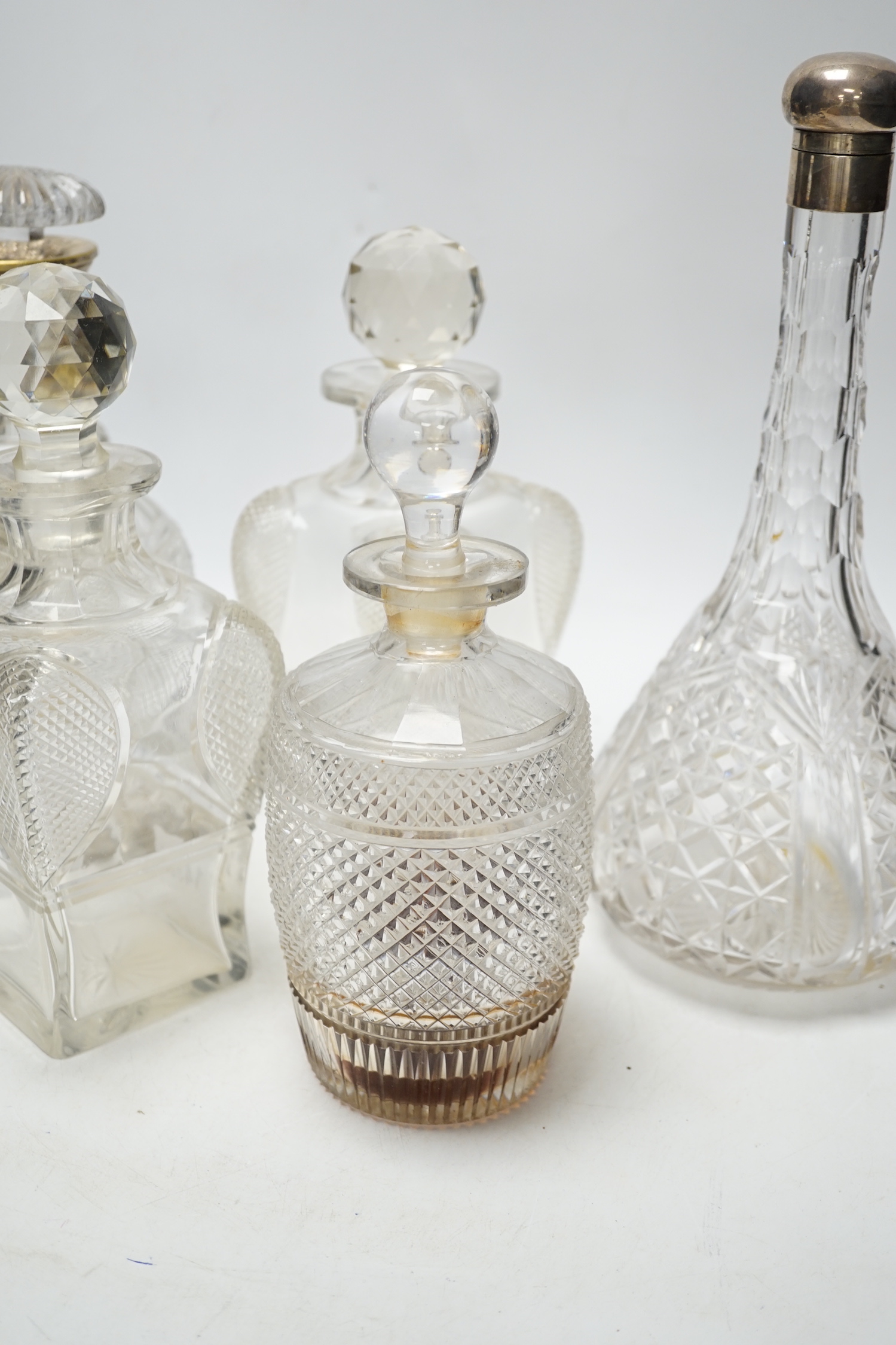 Two silver mounted glass decanters, a pair of waisted cut glass decanters and one other, tallest 29cm high (5)